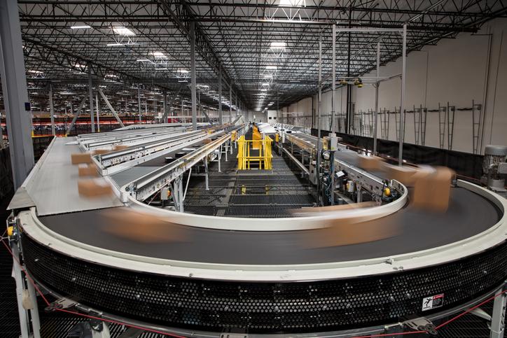 Boxes speed by on a conveyor belt in a warehouse with no humans around. 