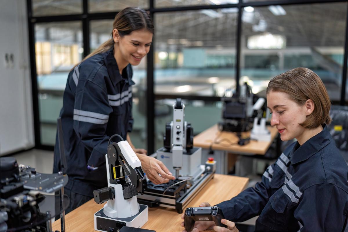 Girl engineer sitting in robot fabrication room quality checking electronic control board 