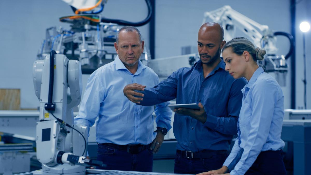 Engineering, tablet and people in discussion in lab with machine for analysis, research and automation.