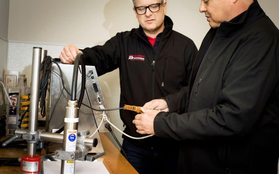 Two men examining a machine between them