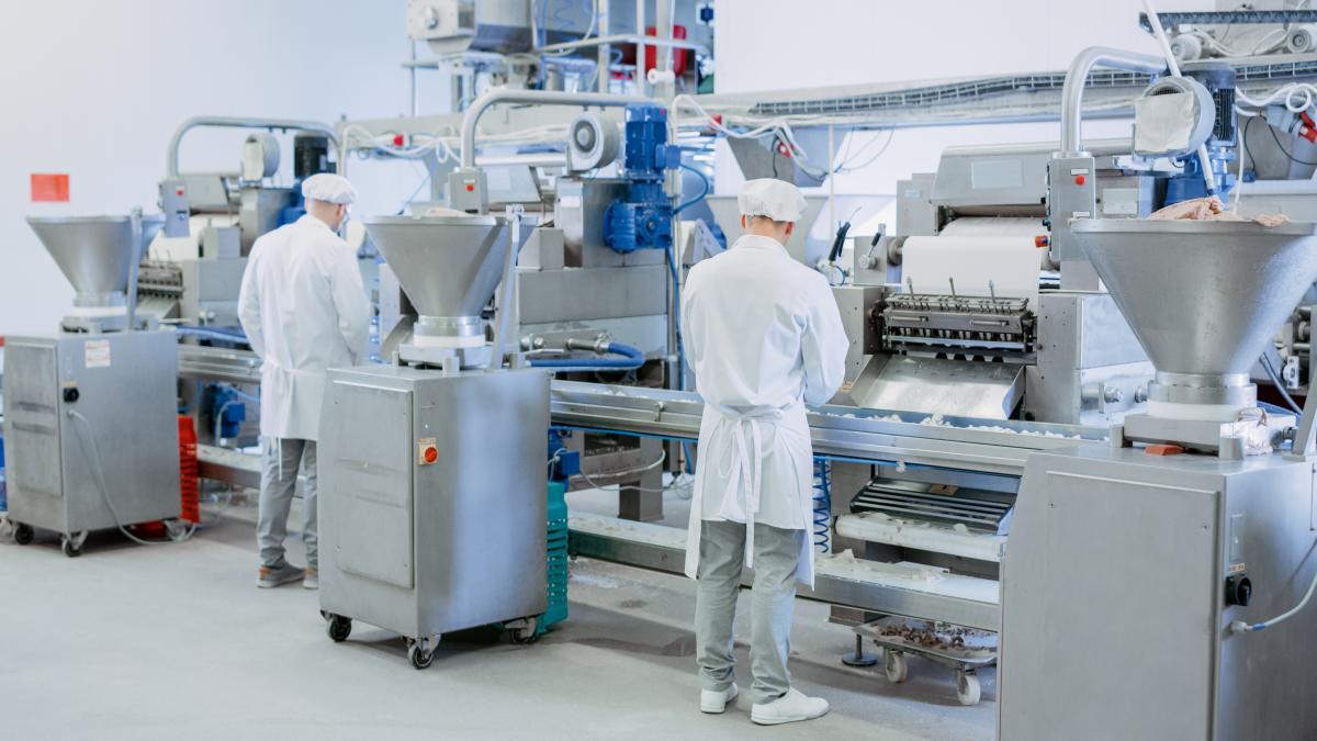 Two people standing over a machine during a packaging equipment repair 