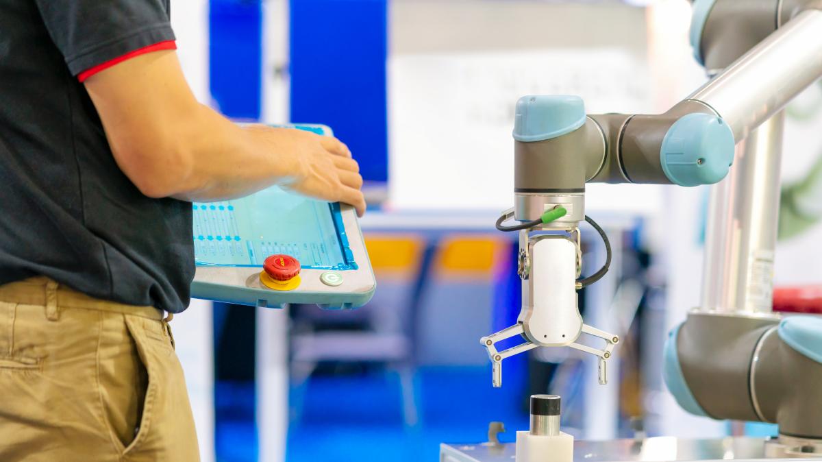 Worker packaging boxes alongside a cobot.