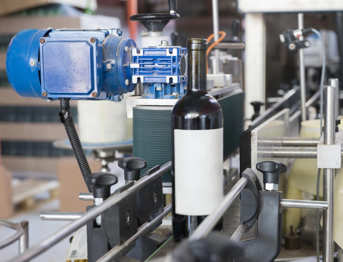 A wine bottle being labeled by an automated wrap around labeler